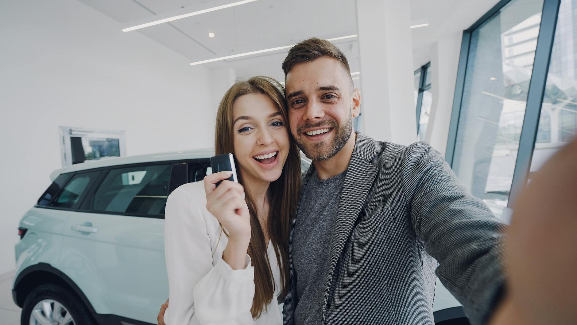 Para robiąca selfie przy świeżo kupionym samochodzie w salonie