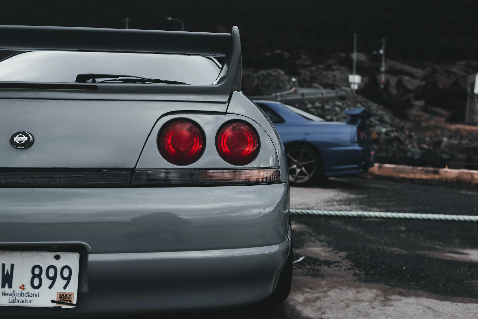 Srebrny Nissan Skyline GT-R zaparkowany w ciemnej miejskiej uliczce