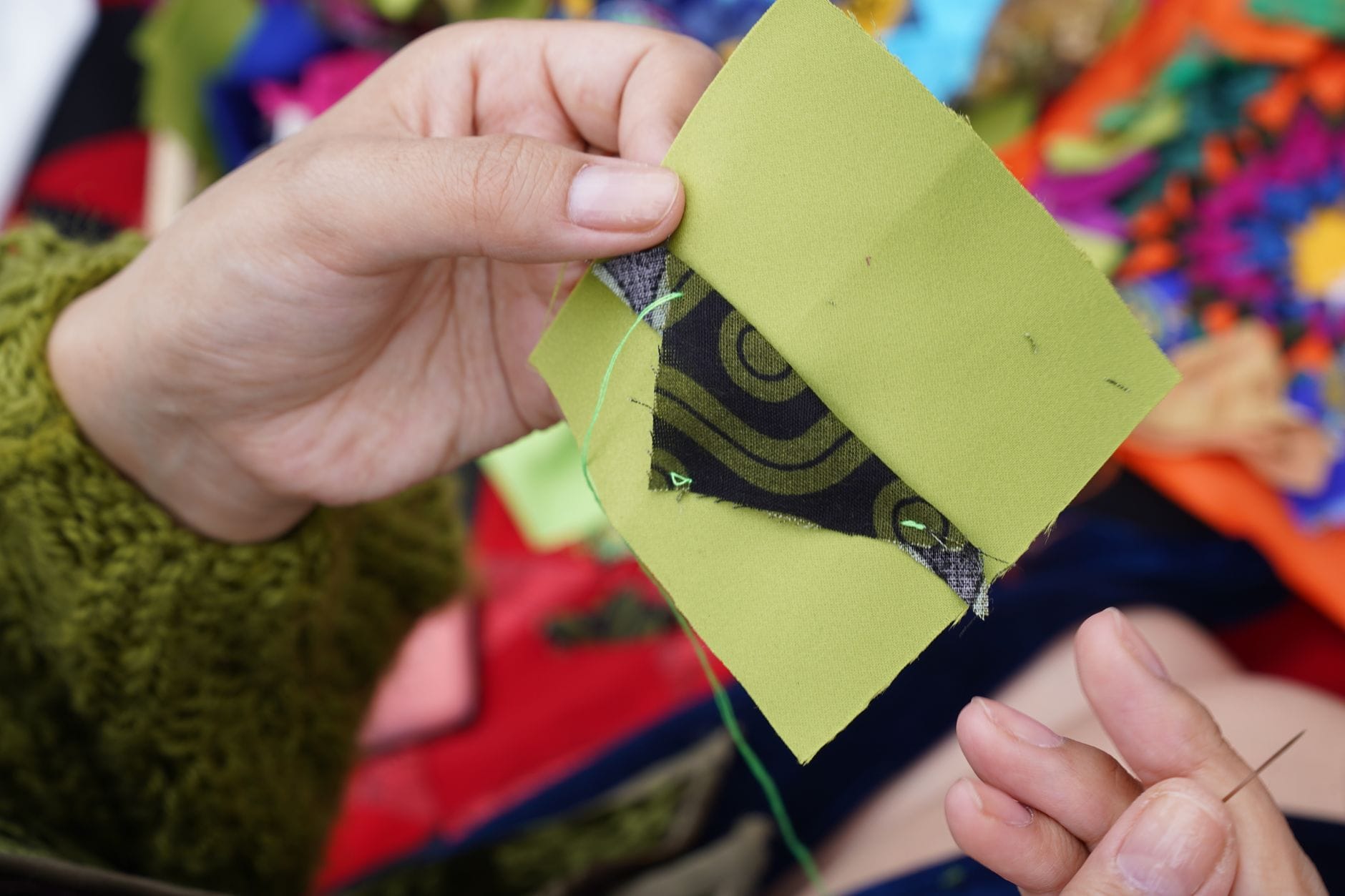 Dłonie szyją patchwork z kolorowych tkanin o ozdobnych wzorach