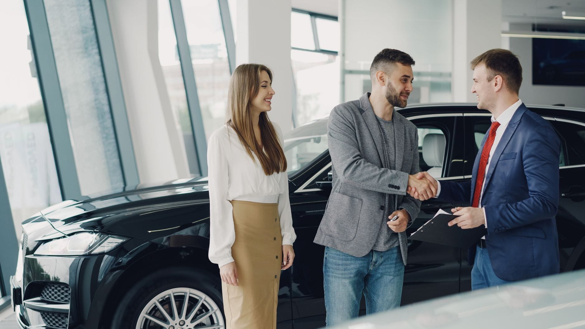Klient podaje dłoń dealerowi w salonie przy zakupie nowego auta