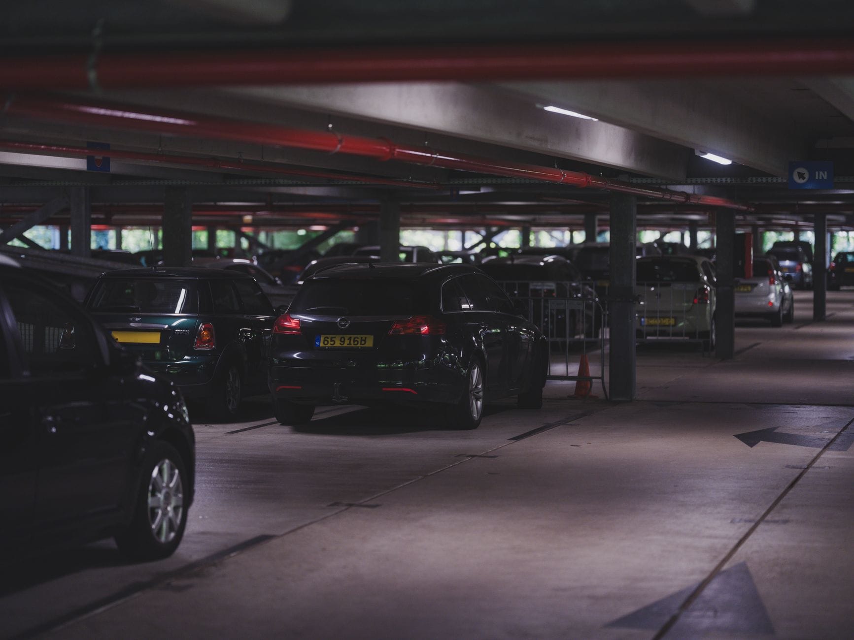 Podziemny parking z szeregiem zaparkowanych nowych samochodów