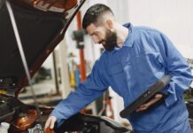 Jak sprawdzić, czy auto nie jest kradzione? Darmowe bazy policji i rejestry międzynarodowe Mechanik w niebieskim kombinezonie sprawdza silnik samochodu w garażu